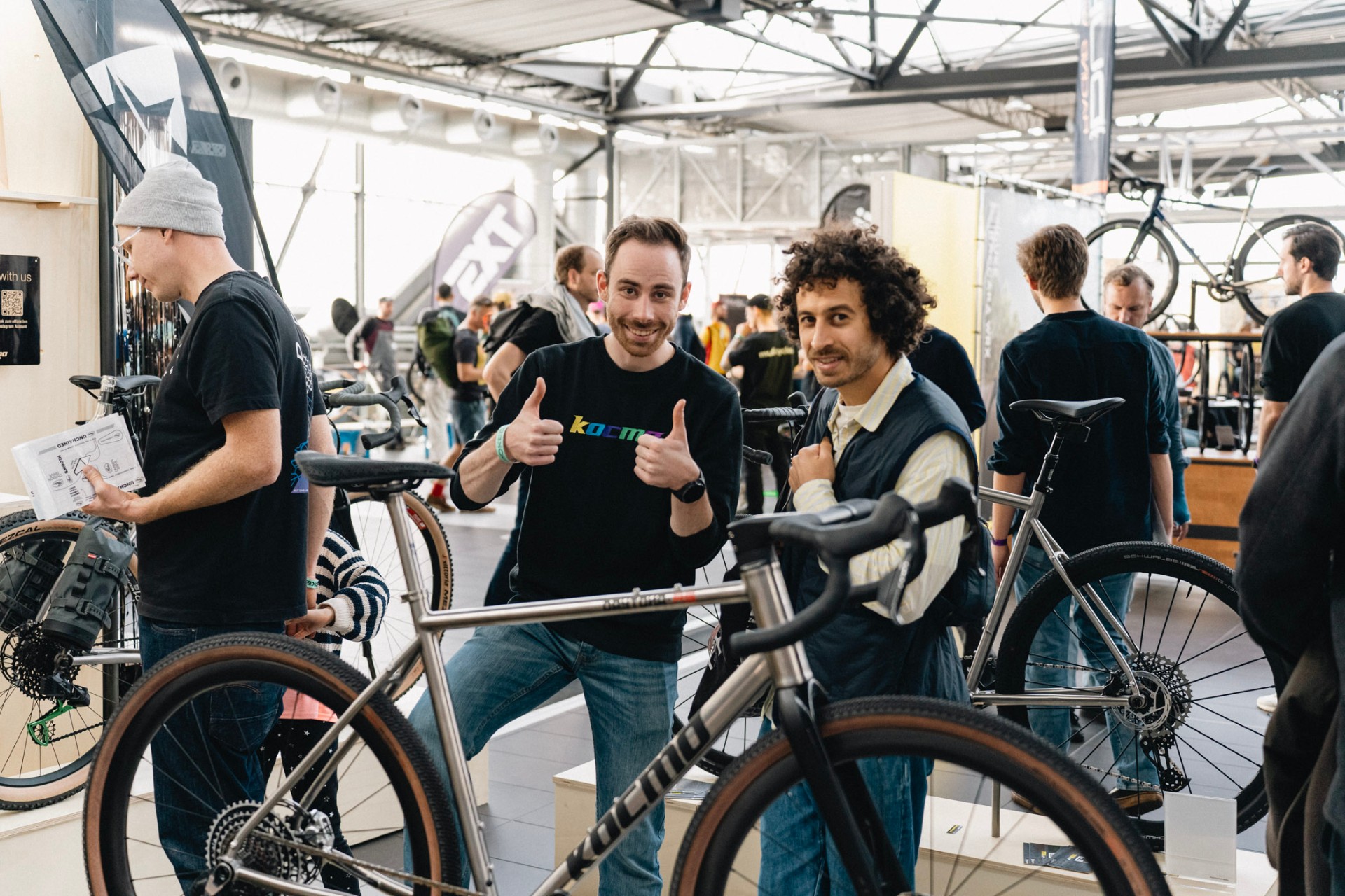 Two visitors giving a thumbs up next to a titanium bicycle