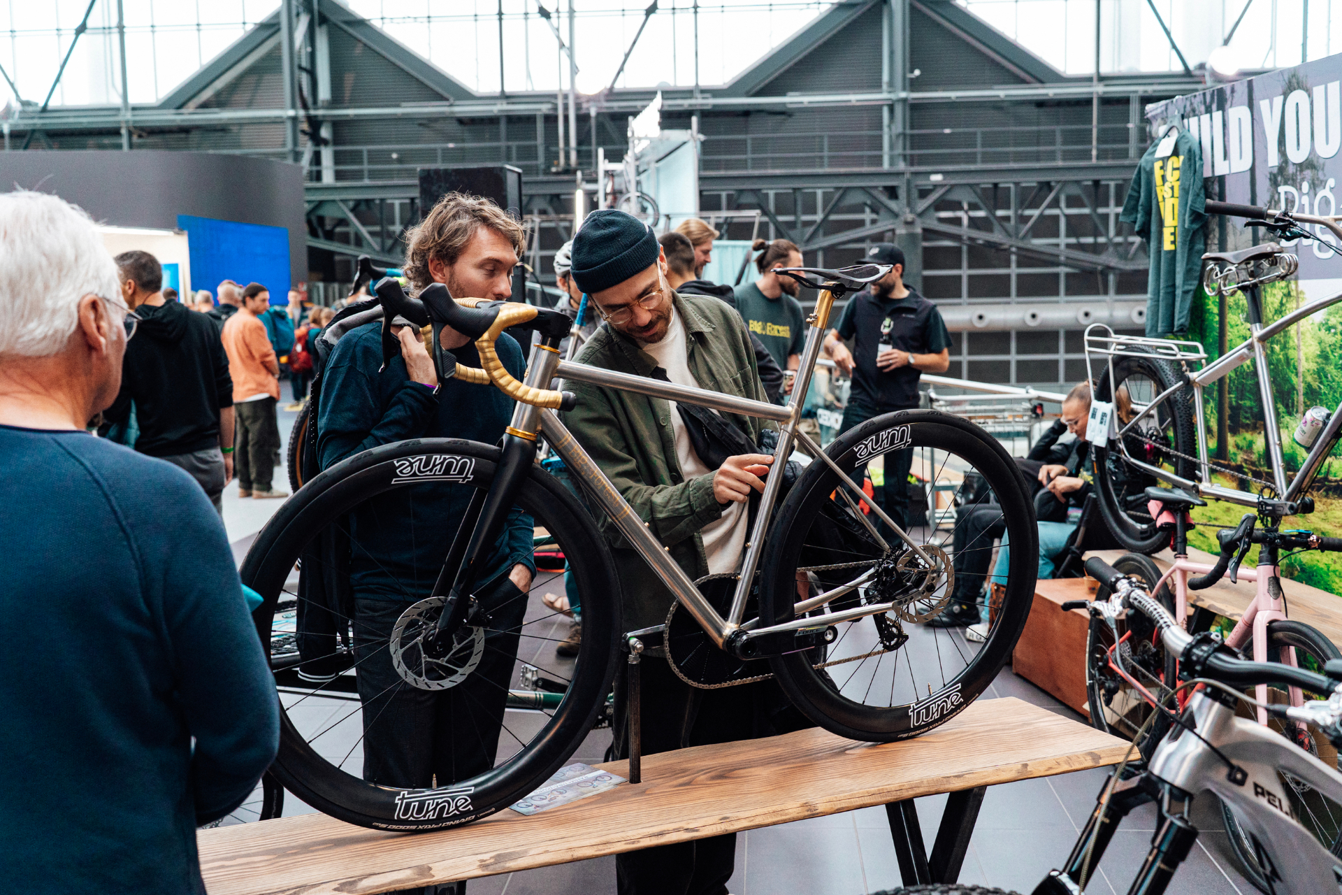 Visitors examining a handmade bicycle on the Bespoked show floor