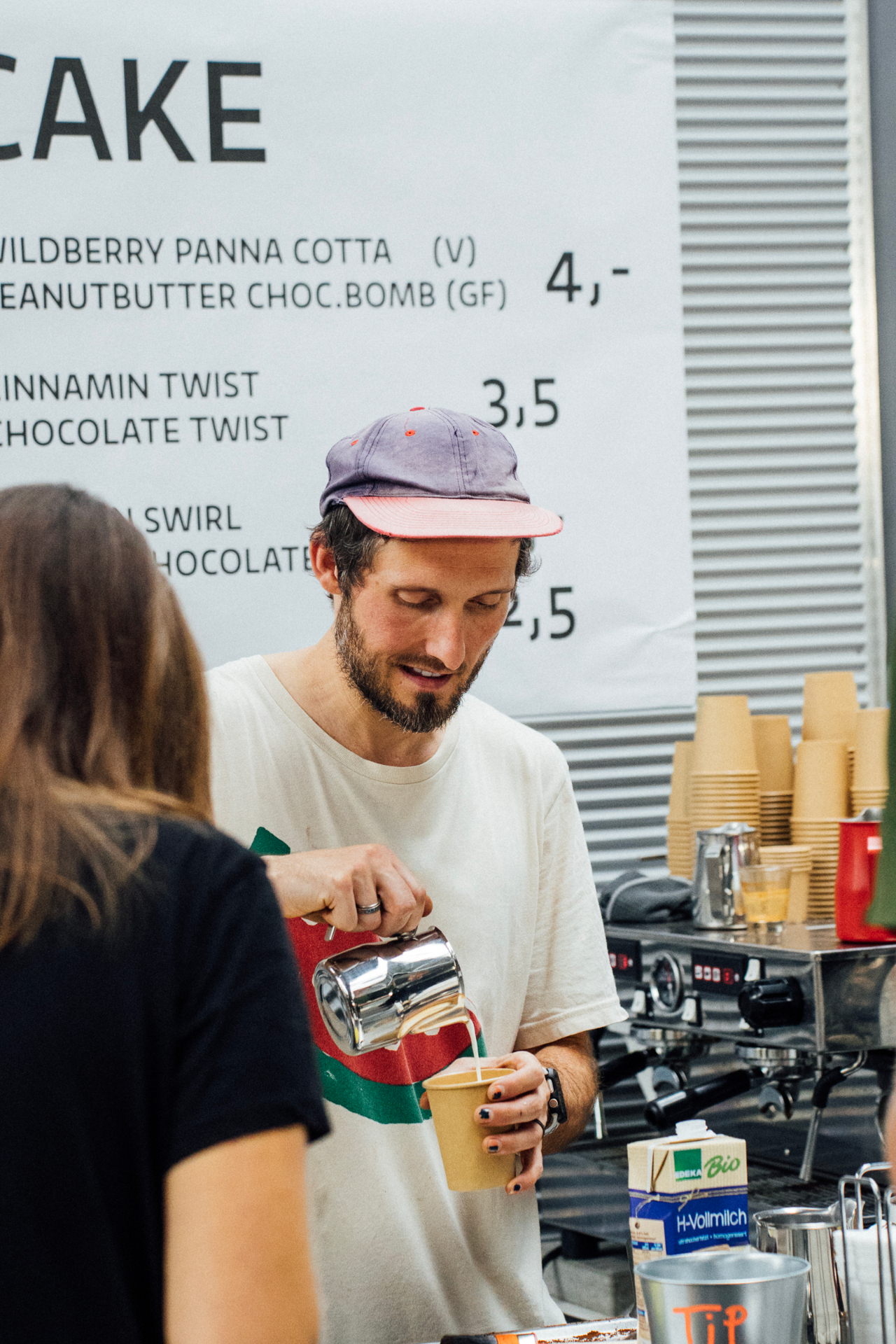 A barista pouring milk into a coffee at the show café